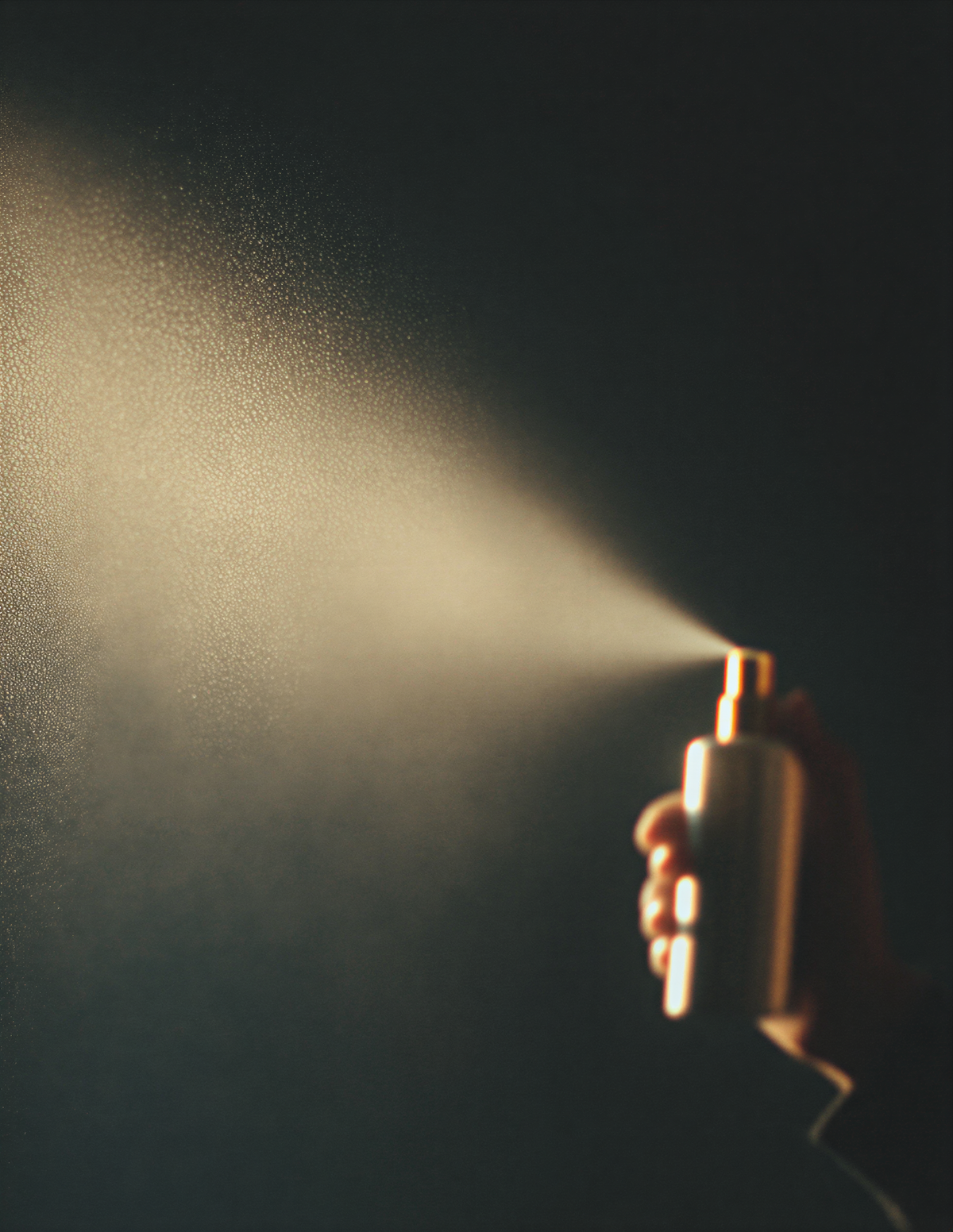 A hand holding a perfume bottle. Spraying perfume. 