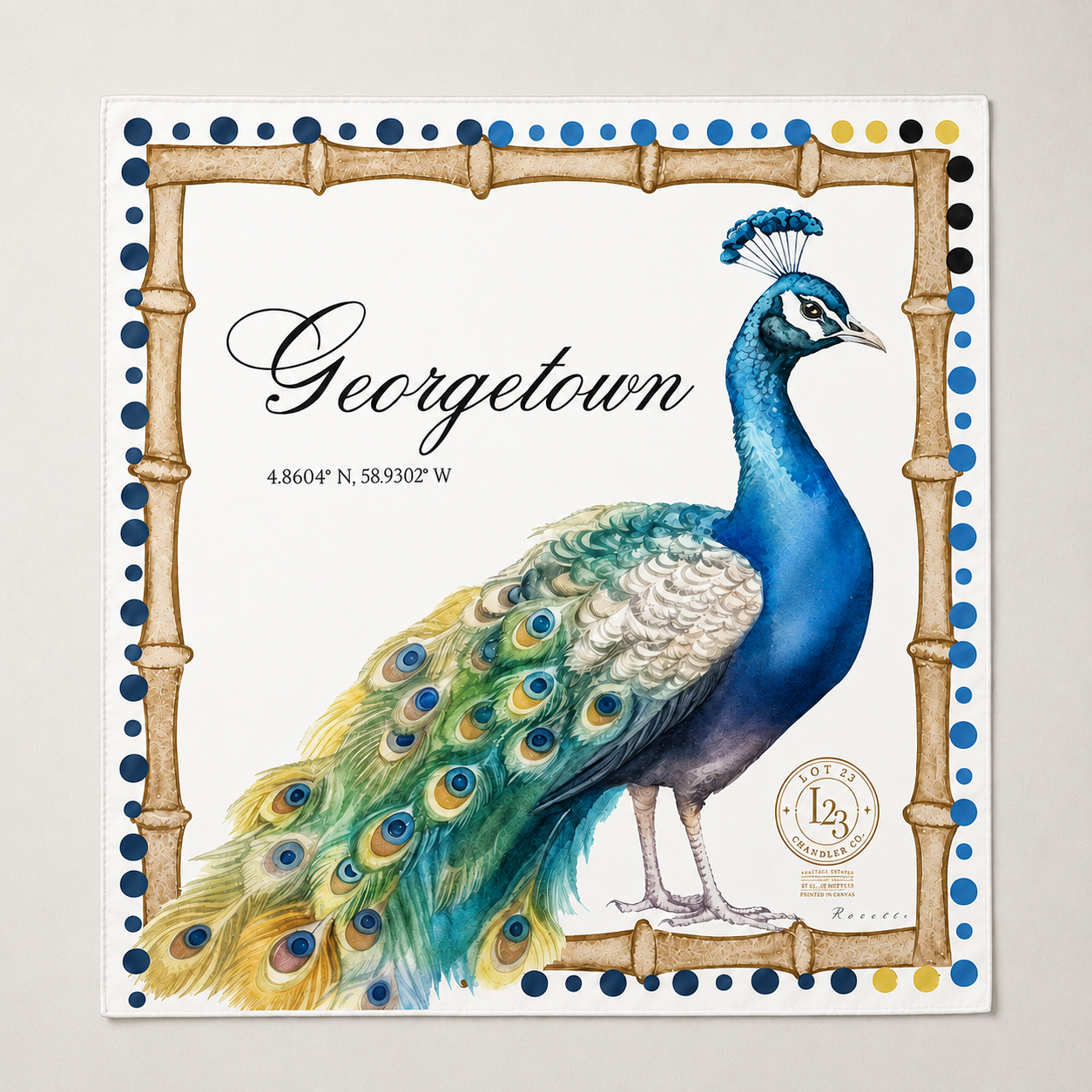 A square decorative print featuring a painted peacock with a bright blue neck and green-and-blue tail, framed by a bamboo-style border with blue dots. The word 'Georgetown' appears in script, with coordinates beneath it and a circular seal near the lower right.