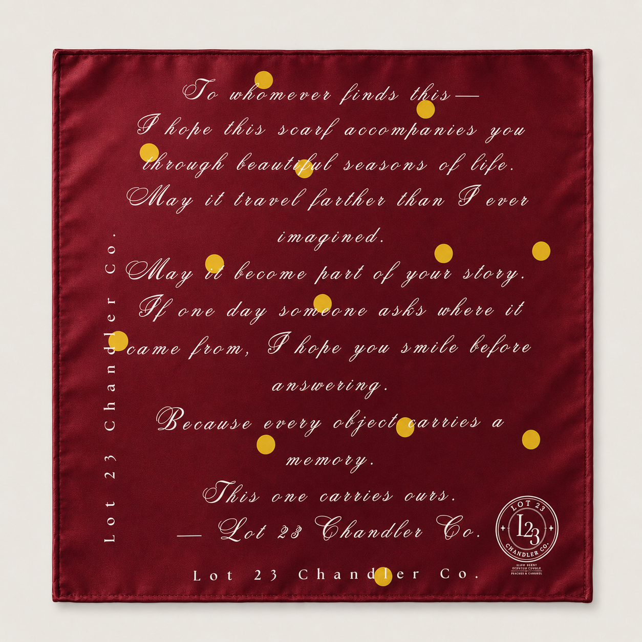 A square burgundy satin scarf with elegant gold cursive text and small gold dots, featuring a quote from Lot 23 Chandler Co. and their brand logo in the bottom right corner.